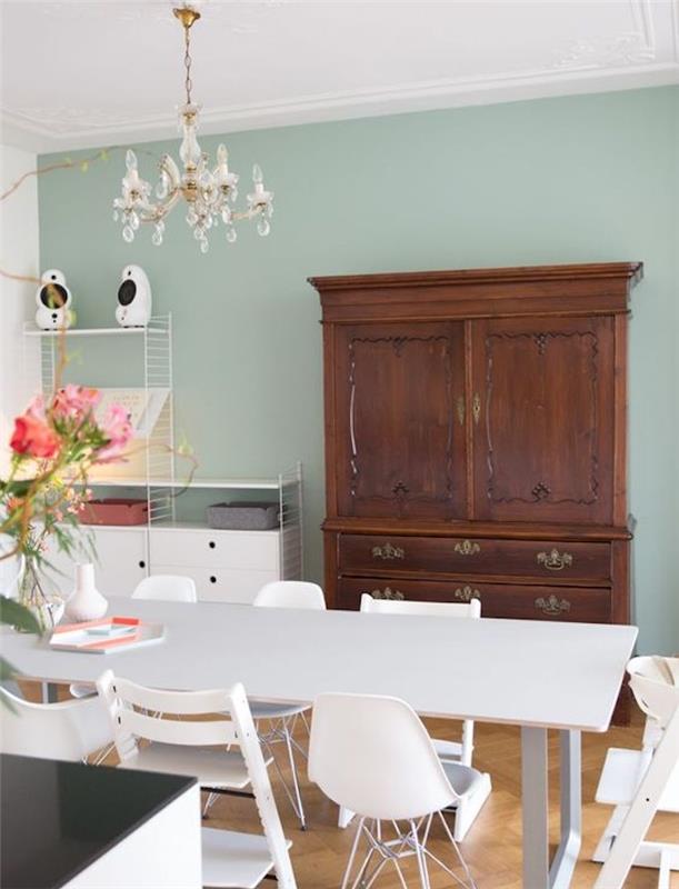dekor jedilnice s svetlo zelenimi stenami iz celadona, jedilna miza in stoli v skandinavskem slogu, vintage lesena omara, eleganten lestenec