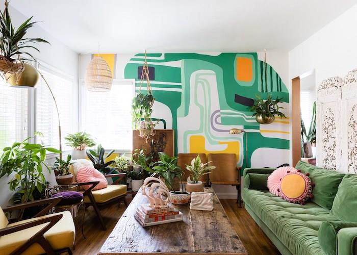 zelena zofa, mizica iz surovega lesa, rumeni naslanjači, naglasna stena prebarvana z geometrijskimi vzorci, zelene rastline