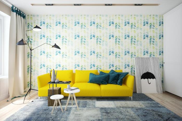 İskandinav oturma odası, çiçekli duvar kağıdı giymiş duvar, mavi, sarı ve yeşil, sarı kanepe, gri ve mavi halı, İskandinav masaları, hafif parke, tasarımcı lambası