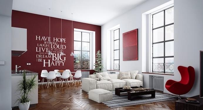 bordo spalvos akcentinė siena virtuvėje-valgomajame, atvira svetainei, valgomojo zona su stikliniu stalu ir skandinaviškomis kėdėmis, baltas virtuvės fasadas, svetainė su balta sofa ir išmatomis, rudas kavos staliukas ir raudonas fotelis
