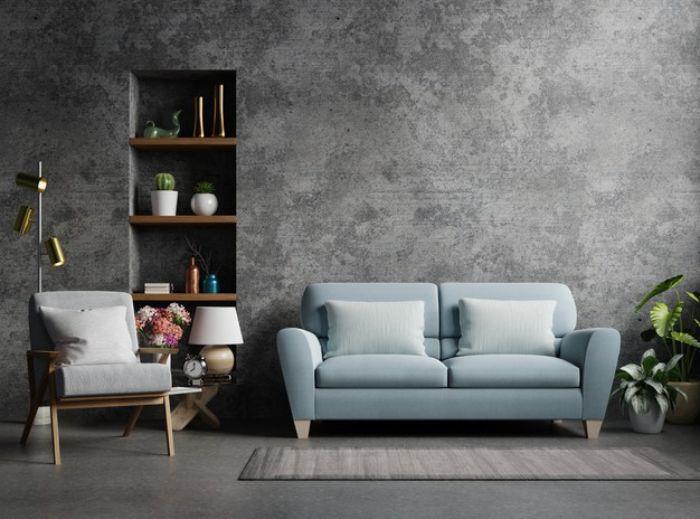 betoninė siena mėlyna sofa pilka fotelio mediena ir metalinės lentynos pilkos grindys pramoninio prašmatnaus dekoro pavyzdys