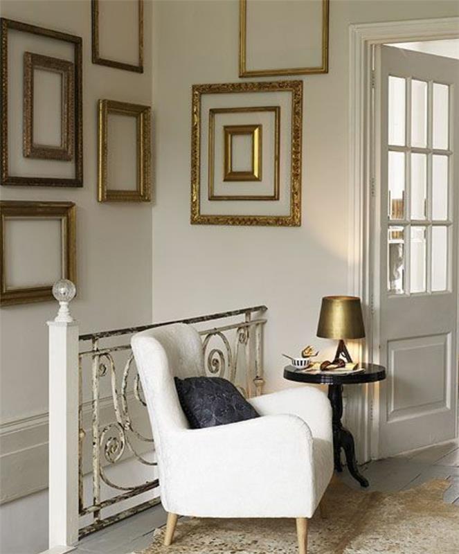 stena iz okvirjev zlatega sijaja, ideja, kako okrasiti stopnišče, beli fotelj, servisna miza, zlata svetilka, usnjena preproga