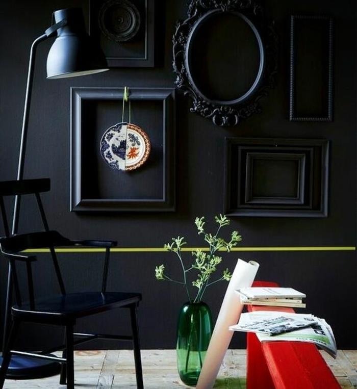 steno prebarvano v črno, okrasite steno s črnimi, ovalnimi in pravokotnimi okvirji, črnim kovinskim stolom, rdečo klopjo, zeleno vazo in parketom iz svetlega lesa, steno iz okvirjev