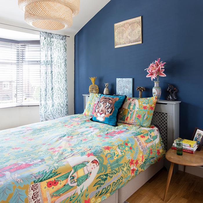 stena v ozadju temno modre barve, pisano posteljnino z eksotičnim tiskom, izvirne najstniške ideje za okrasitev spalnice