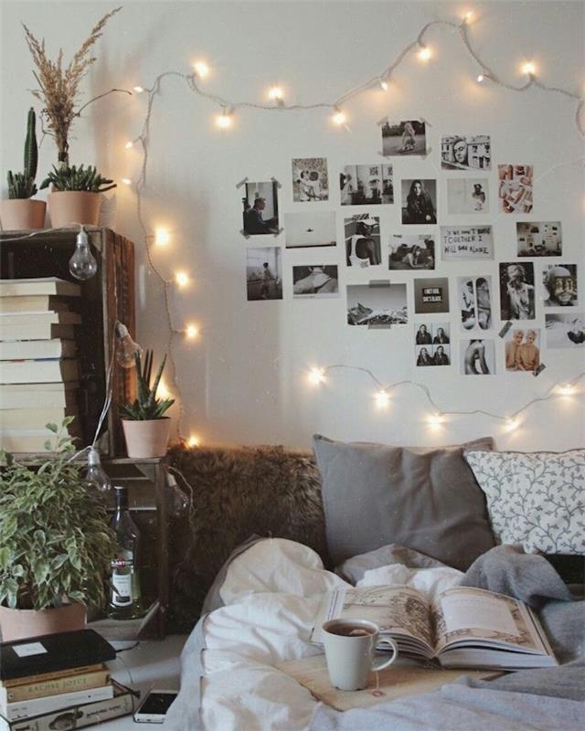 galvūgalis nespalvotose nuotraukose, apsuptas šviesios girliandos, prie lovos esanti medinė lentynėlė knygoms, pilka ir balta lininė medžiaga