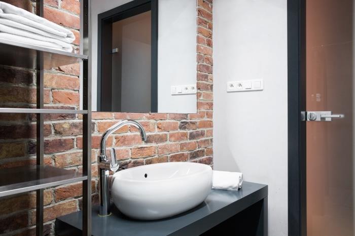 postavitev majhne kopalniške omare z omejenim prostorom s stenami iz rdeče opeke s kovinskimi in mat črnimi oblikovalskimi omarami