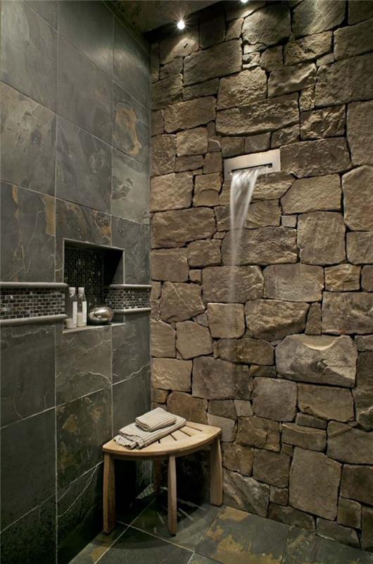 dizaino ir originalus vonios kambarys su dušu akmens sienoje ir plytelėmis išklotomis grindimis