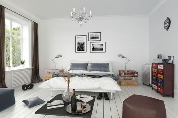 baltos sienos ir grindų aukšta pėdų lova-komoda fasadas dekoruotas-įvairiaspalvis-pilkas-pagalvių užvalkalai-dekoratyviniai-lagaminai-krūvose-kaip naktinis stalas