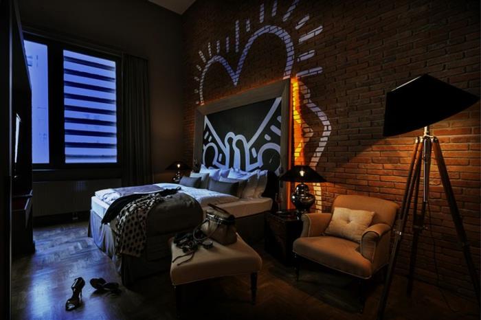izvirna spalnica za odrasle, opečna stena, beli srčni grafiti, industrijsko elegantno vzdušje