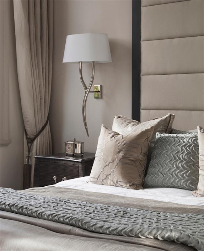 biserno pobarvana stena, siva postelja in sivo in rjavo posteljnina, bela svetilka, nočna omarica z rjavimi lesenimi predali