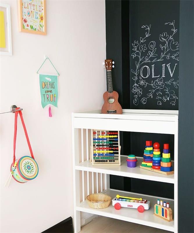 siena iš šiferio dažų, kad vaikas galėtų ant jos piešti, maža žaislų saugykla, balta siena, papuošta vaikų piešiniais ir dekoracijomis