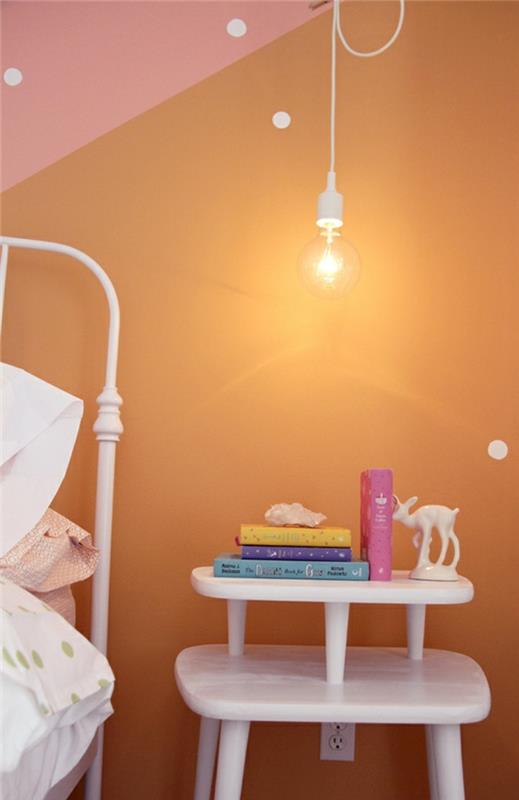 çıplak ampullü beyaz başucu sarkıt lamba, pembe ve turuncu iki tonlu duvarlara sahip orijinal bir çocuk yatak odası