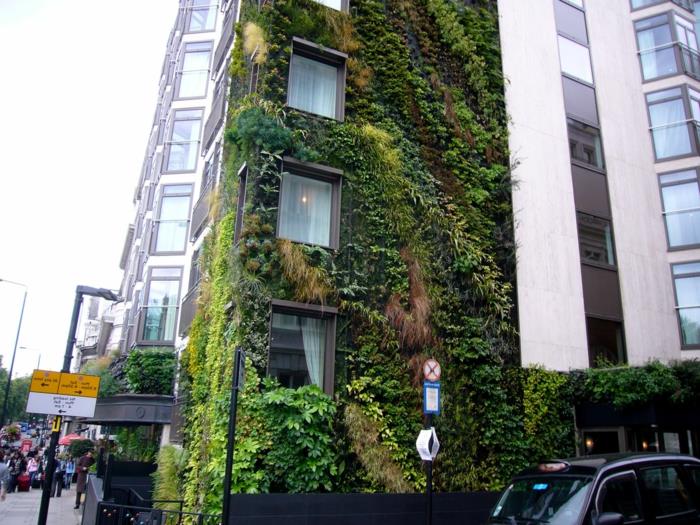 žalia mieste, vertikalus auginimas su žaliais, raudonais ir geltonais augalais, viešbutis su siena, padengta augalais, išorinė augalinė siena