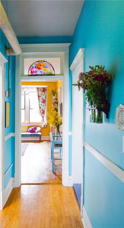 okrasni ozek hodnik s stenami, pobarvanimi v svetlo turkizno modro barvo, ki gleda na curry rumeno dnevno sobo