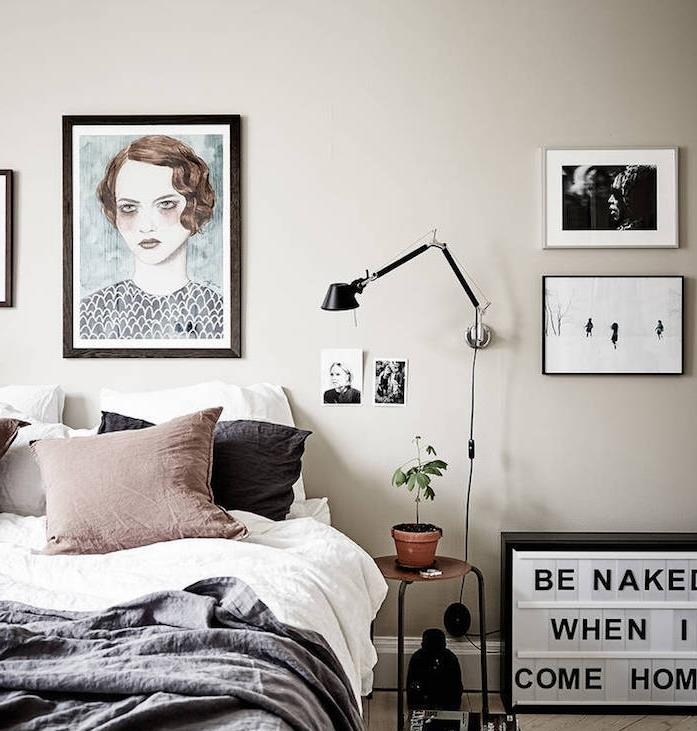 lahka taupe spalnica, ogljeno sivo -belo posteljnina, rjava blazina, biserno sive stene, grege senca, stenska dekoracija s portretno risbo