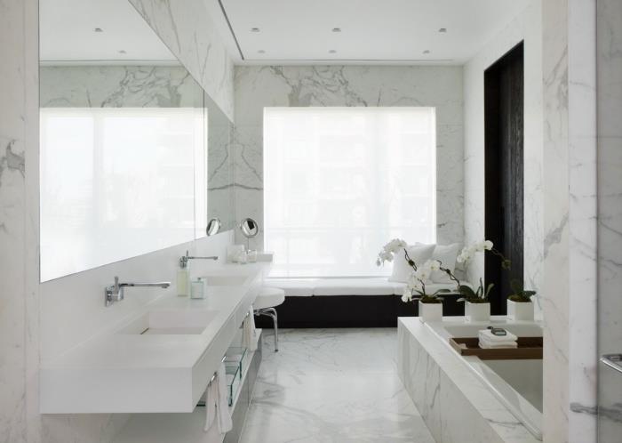 Büyük aynalı ve çift lavabolu mermer tasarım duvarlara sahip banyoda şık ve lüks iç tasarım