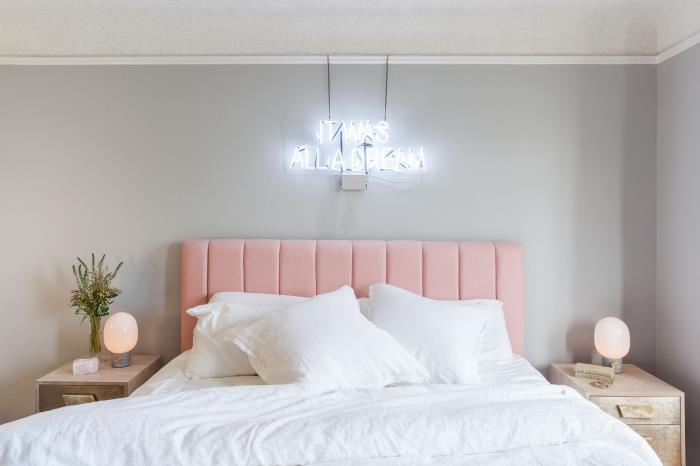 pagrindinio miegamojo dekoro idėja su šviesiai pilkomis sienomis ir baltomis lubomis, apstatytomis šviesiais mediniais baldais ir rausva lova