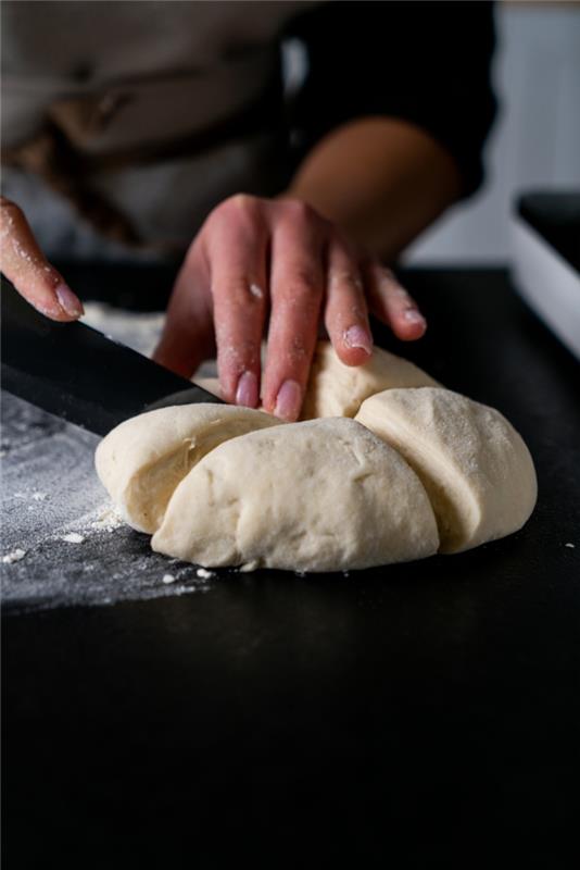 naan ekmeği tarifi, hamur keskin bıçakla dörde bölünmüş, siyah yüzeye yerleştirilmiş, unla kaplanmış
