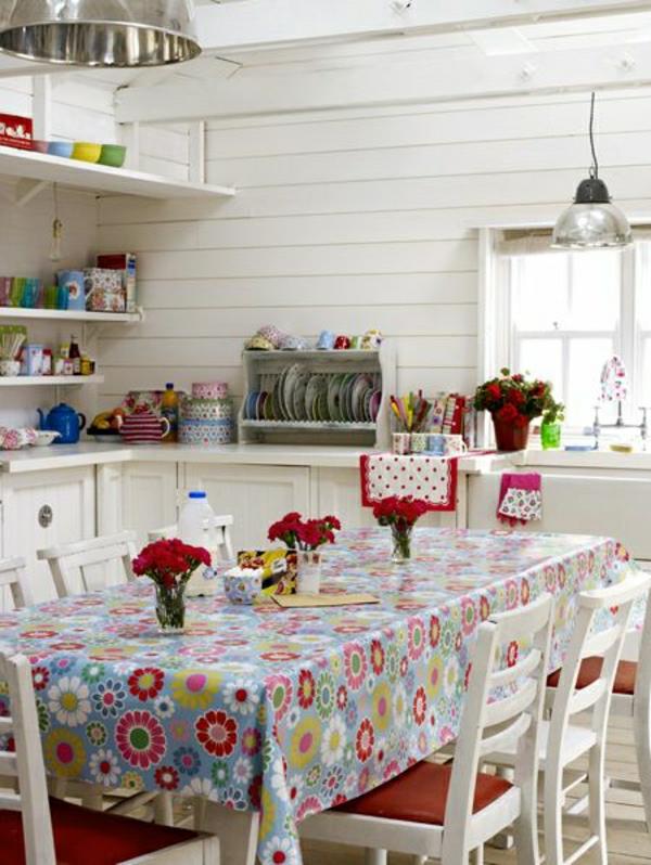 staltiesė-vaškuotos-gėlės-pieštos-staltiesės spalvos-medinės-kėdės-balta-virtuvė-svetainė