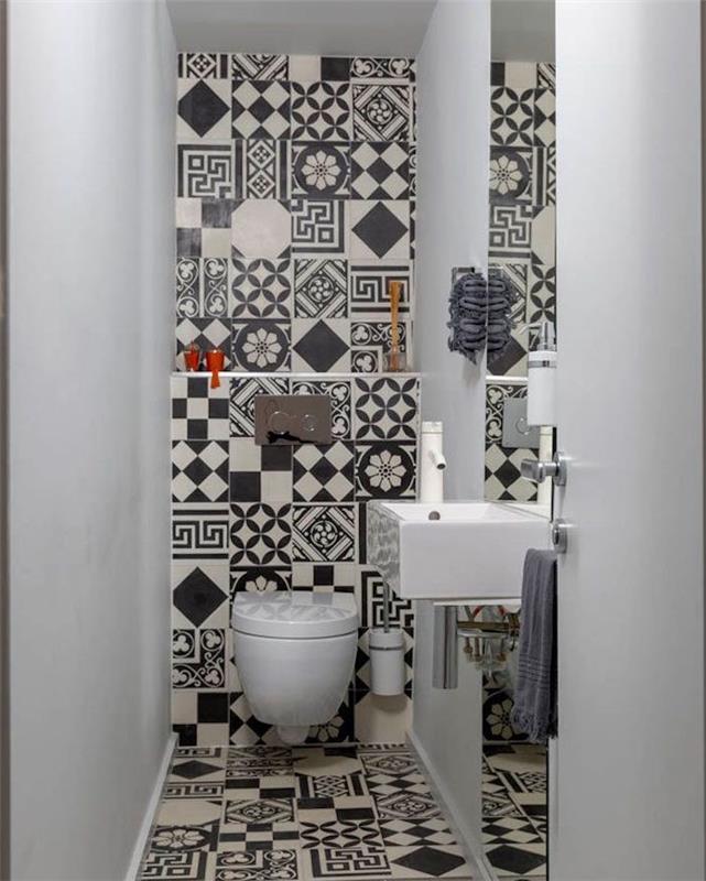 prenova kopalnice, ozko stranišče z dvema belima stenama, tretja stena in tla so prekrita s črno -belimi, neusklajenimi in vzorčnimi ploščicami, pravokotnim belim umivalnikom in navadno straniščno školjko