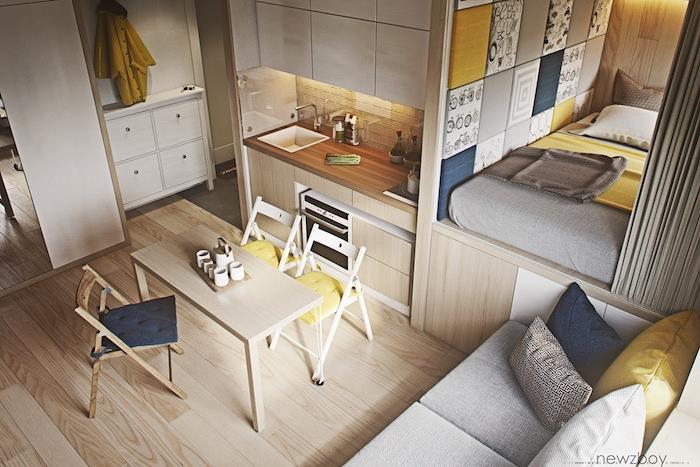 virtuvės išdėstymas maža medinė virtuvė su valgomuoju su mediniais baldais, lovos čiužinys ant platformos, paslėptas pilka užuolaida, pilki, geltoni ir mėlyni deko akcentai