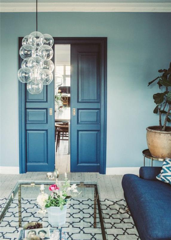 bencinsko modra dnevna soba z visokimi vrati v modro sivi modri barvi moderno vzdušje s svetilko z velikimi prozornimi steklenimi kroglami