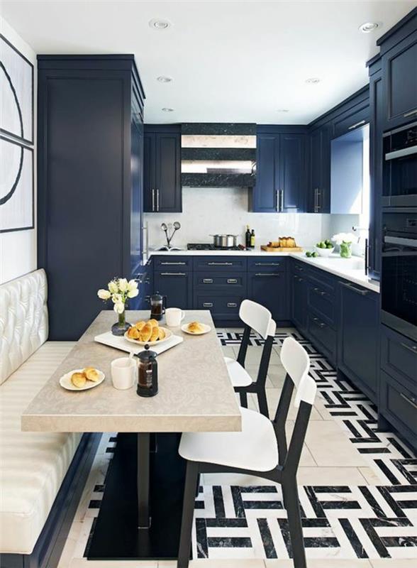 modro -modra kuhinja s pohištvom v sivo -modri barvi in ​​črno -belo mizo ter stoli v bež barvi
