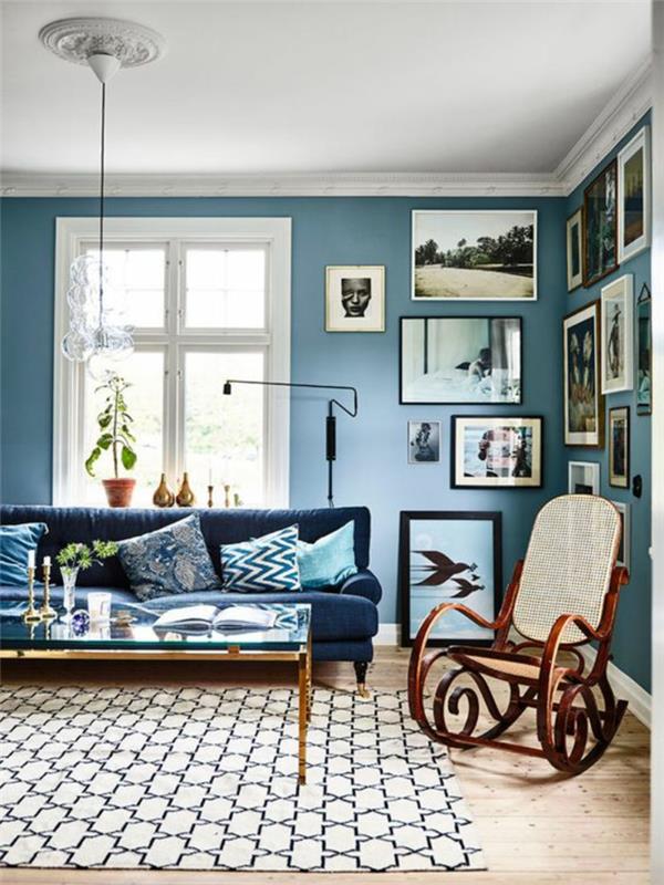 modra soba za odrasle z vrtljivo sobo v beli in modri barvi z dolgim ​​kavčem v račji modri barvi in ​​stenami, okrašenimi s slikami