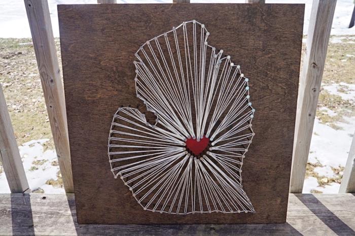 tamsios medinės lentos modelis su kūryba baltu siūlu ir maža raudona širdelė centre kaip pasidaryk pats objektas