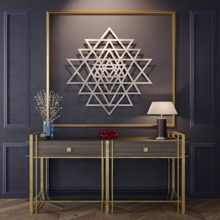 stilinga dekoratyvinė idėja prieškambaryje su tamsiomis sienomis ir medinėmis grindimis, apstatytomis mediniais ir auksiniais baldais, graži metalinė apdaila su trikampiais raštais