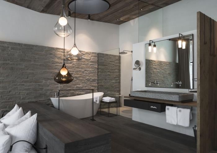 kmečki in sodoben dekor v kopalnici s sivim lesenim podom in kamnito steno ter belo barvo