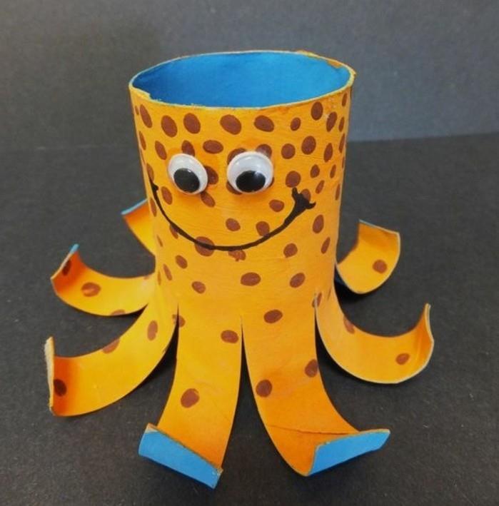 nasmejan okrasni hobotnica, narejen iz straniščne rolice, pobarvan v oranžni in modri barvi, okrašen z markerjem in nalepljenimi očmi