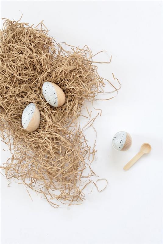 Velykų puošmena su mediniais kiaušiniais, dekoruotais dviejų spalvų baltos ir smėlio spalvos dizainu, medinių kiaušinių modeliu
