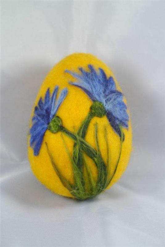 Velykinis kiaušinis, geltonas kiaušinis su veltomis mėlynomis gėlėmis ant pagrindo
