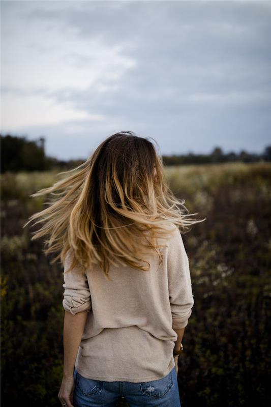 balayage na rjavih laseh, bež bluza in denim hlače, ženska pričeska s temnimi koreninami