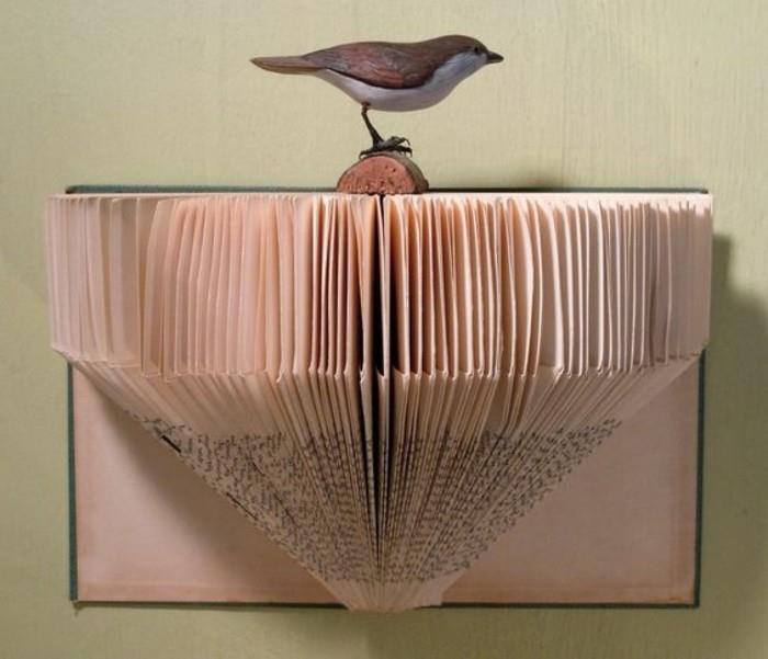 papirna umetnost, narejena iz izrezanih in prepognjenih starodobnih knjižnih strani, prilepljenih na eno od platnic knjige, okrašenih z realističnim ptičjim ornamentom