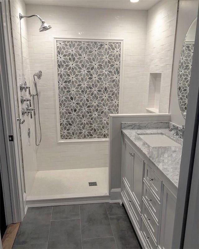Çiçek şeklinde cilalı taşlarla süslenmiş duvar, gri banyo ve lavabonun üstünde beyaz mermer, İtalyan duşu