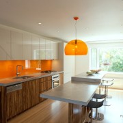 明るいキッチンのインテリアにオレンジ色のエプロンとペンダントランプ