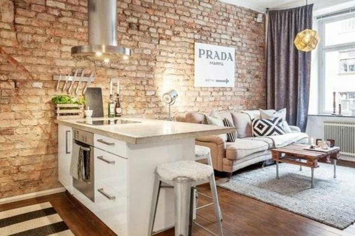 una penisola bianca con top beige, un divano beige, pareti con mattoni a vista: un'idea per arredare mini apartmaji