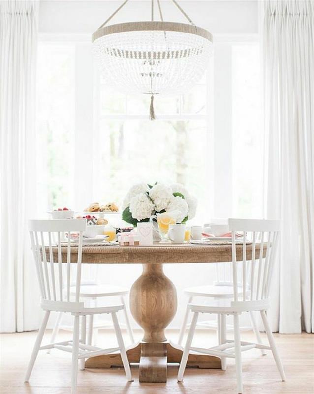 originalus-virtuvės-stalas-šviesaus medžio-medinės-kėdės-baltos-gėlės-ant lango stalo