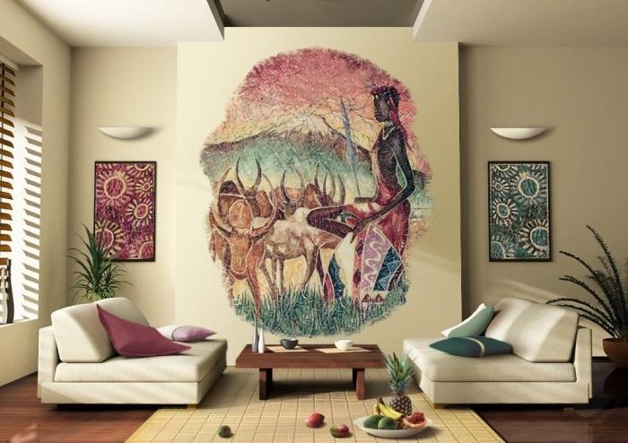 Afrikos dvasia smėlio spalvos svetainėje, apstatyta žemomis sofomis ir tamsaus medžio kavos staliuku, sienų apdaila su Afrikos kraštovaizdžio tapyba