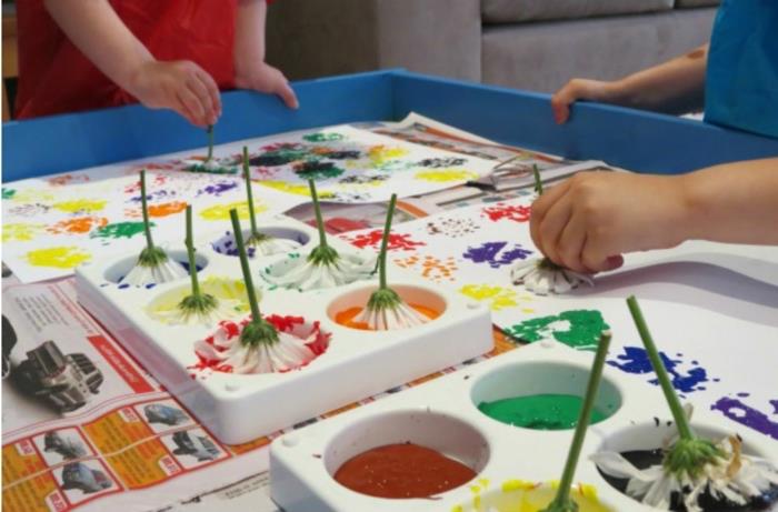 vaikai, tapantys gėlėmis, užsiėmę rankomis, oranžiniai ir raudoni, geltoni ir violetiniai dažai