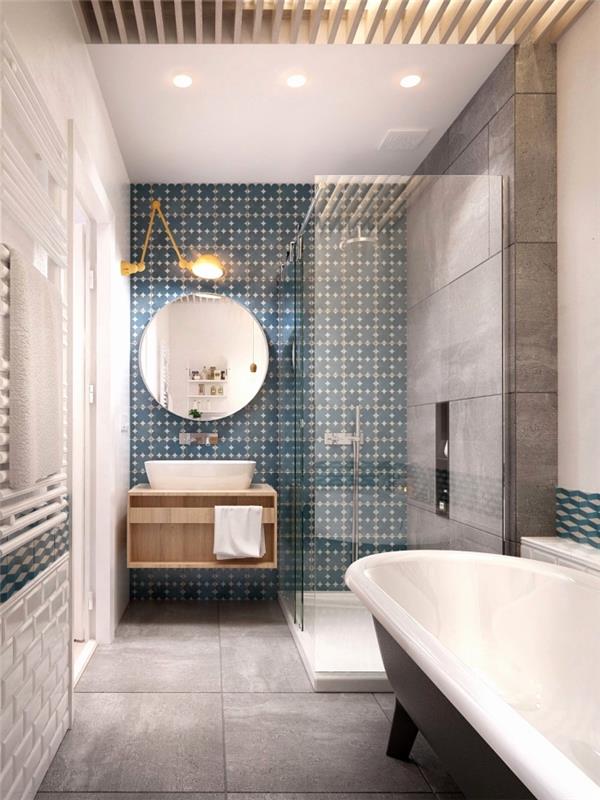 modernus pilkos spalvos vonios kambarys su subtiliai raštuotomis melsvos spalvos cemento plytelių molio keramikos detalėmis, kurios apibrėžia erdvę už kriauklės