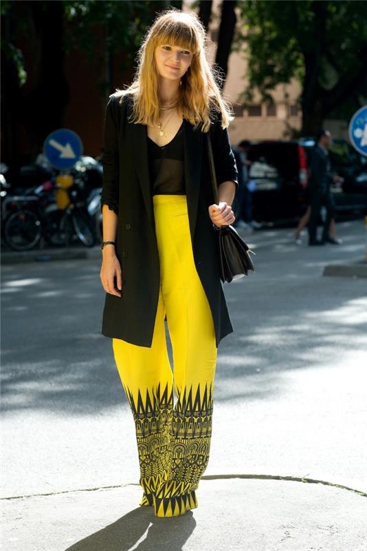 apranga skystomis kelnėmis moteriai, apsirengusiai geltona spalva, dekoruota geometriniais raštais juodos spalvos ir plačiu švarku