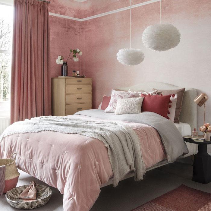 primer roza in belih ozadij za spalnico, rožnato, sivo in rdeče posteljno perilo, oblikovalske bele viseče luči, lesena komoda