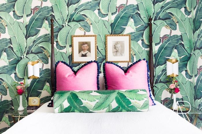 tapete za spalnico s tropskim junge vzorcem, belo posteljnino, roza blazine, šopek svežega cvetja