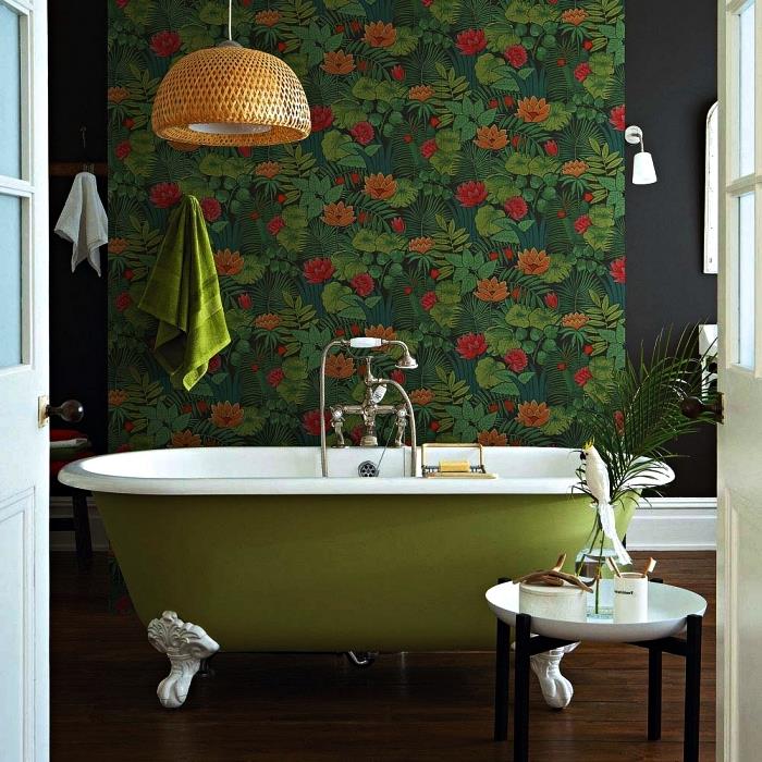 naravna kopalnica s sproščujočim vzdušjem s starinsko zeleno kadjo, poudarjeno z odsekom stene v tropskem ozadju, intimno vzdušje v kopalnici s temnimi toni in rastlinskimi poudarki