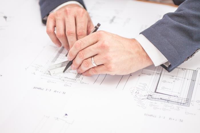 architektas, kuris rašo svetainės ataskaitą su statybos lygio pakeitimais popierine versija