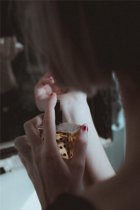 Elinde parfüm şişesi olan kadın, hediye olarak hangi parfümü seçeceğine dair fikir