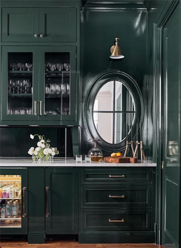 sodoben dizajn v temno zeleno pobarvani kuhinji s temnim pohištvom in belo delovno ploščo